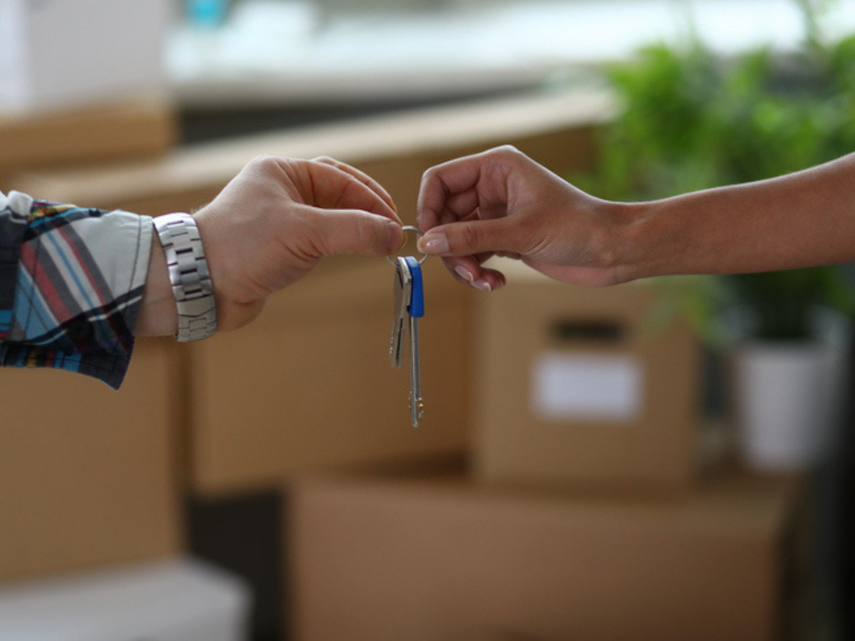 A close-up of a new homeowner receiving keys, a great reminder to budget for the cost of home insurance.