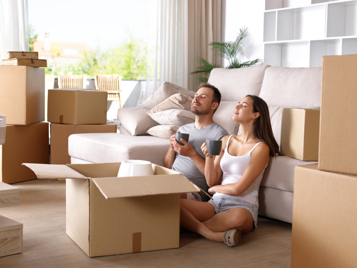 Couple relaxing in a new apartment surrounded by moving boxes representing renters settling into a new home