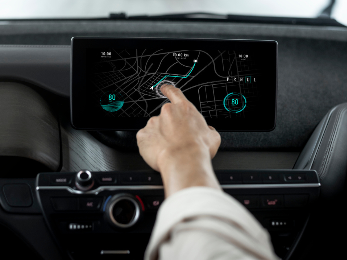 Driver using a vehicle navigation screen to plan a route during Winter Driving conditions.
