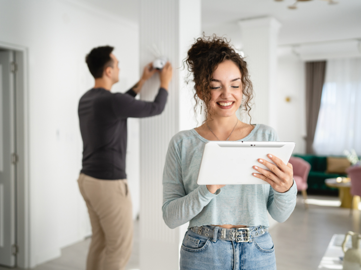 Home Security camera installation while a homeowner reviews settings on a tablet