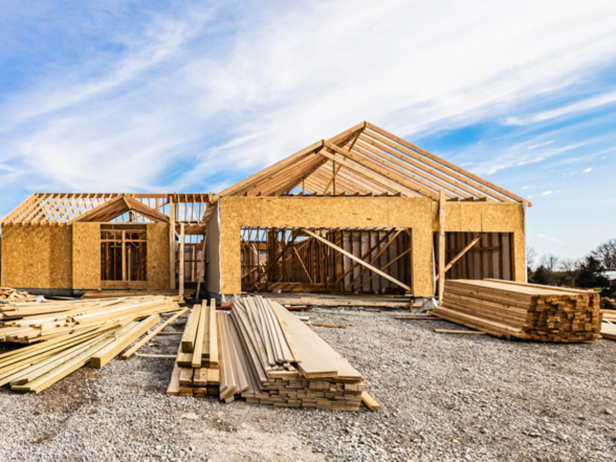 Wood frame house under construction with stacks of lumber, illustrating projects covered by builder's risk insurance.