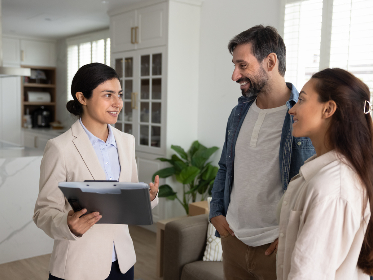 Female insurance agent reviewing tenant insurance options with a couple in a modern apartment