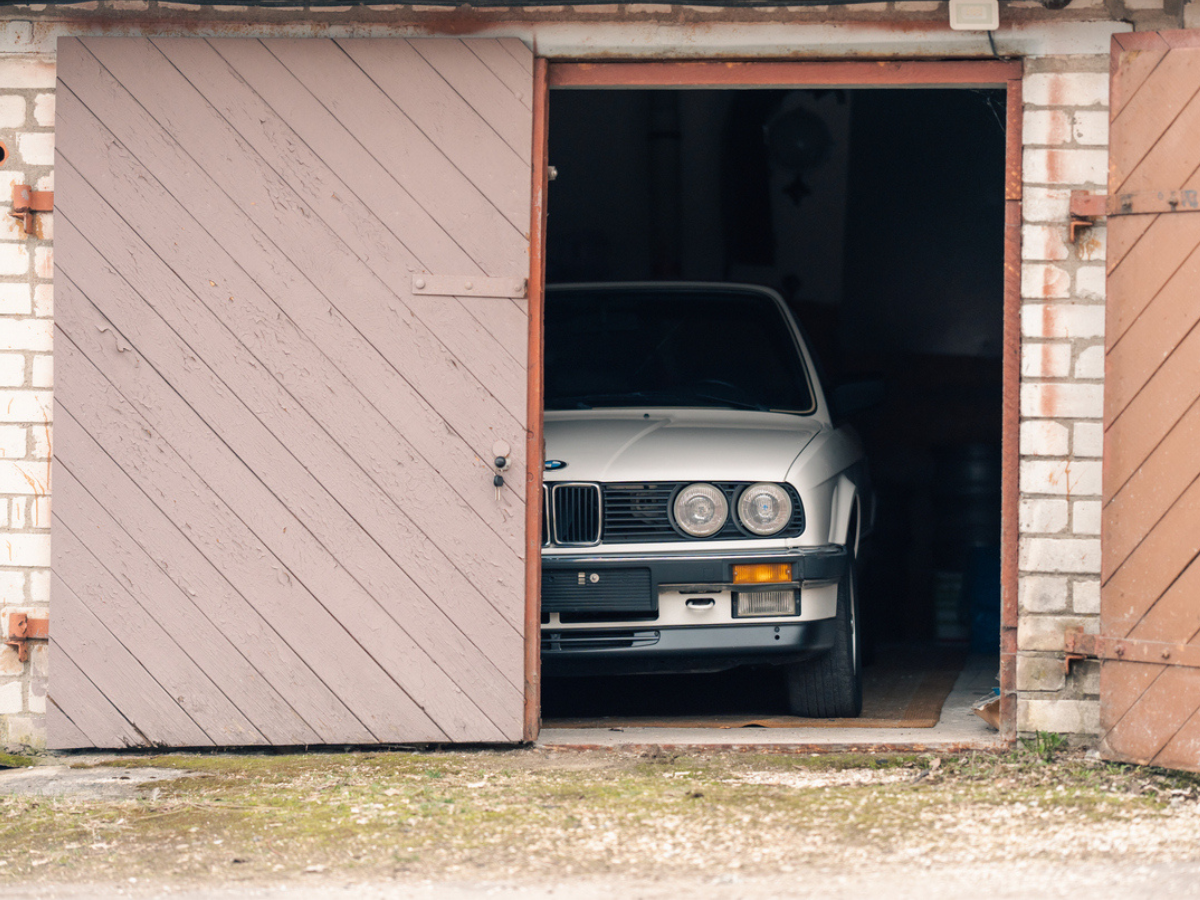 Restored car stored inside a garage with wooden doors, highlighting secure storage for classic vehicle insurance