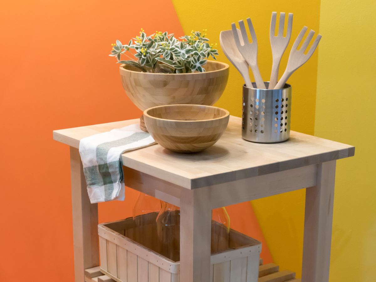 Tenant kitchen setup with wooden bowls, cooking utensils, and a compact storage cart