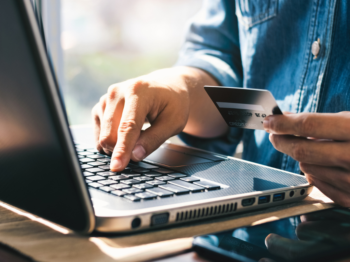 Person using a laptop while holding a credit card for an online transaction.