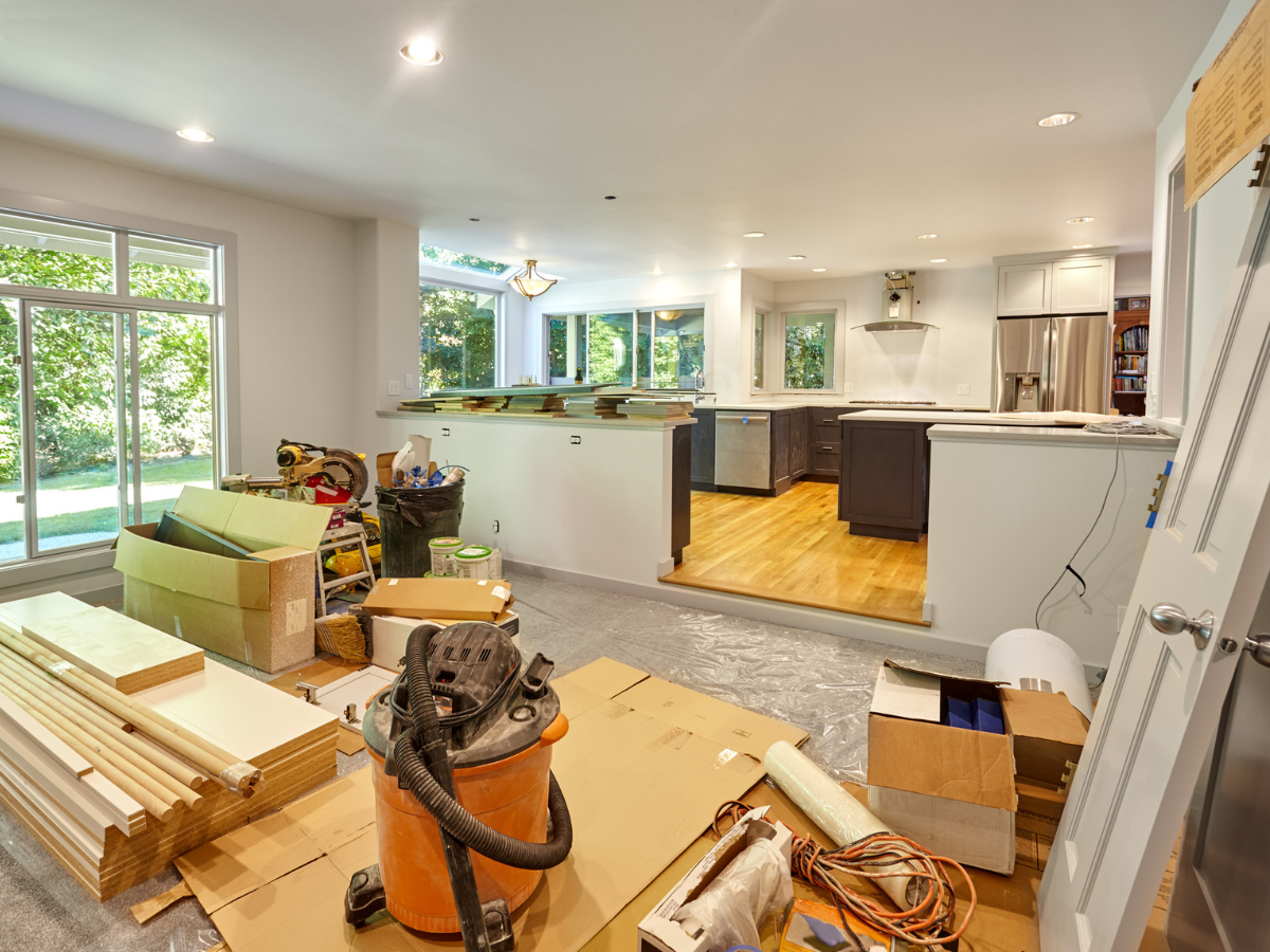 Renovation materials and tools arranged in an open-concept kitchen during a home remodel.