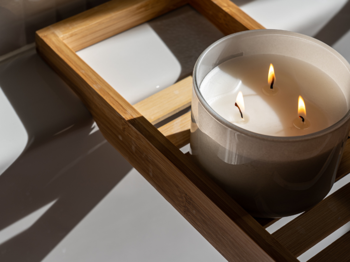 Three-wick Candle burning on a wooden tray in natural sunlight