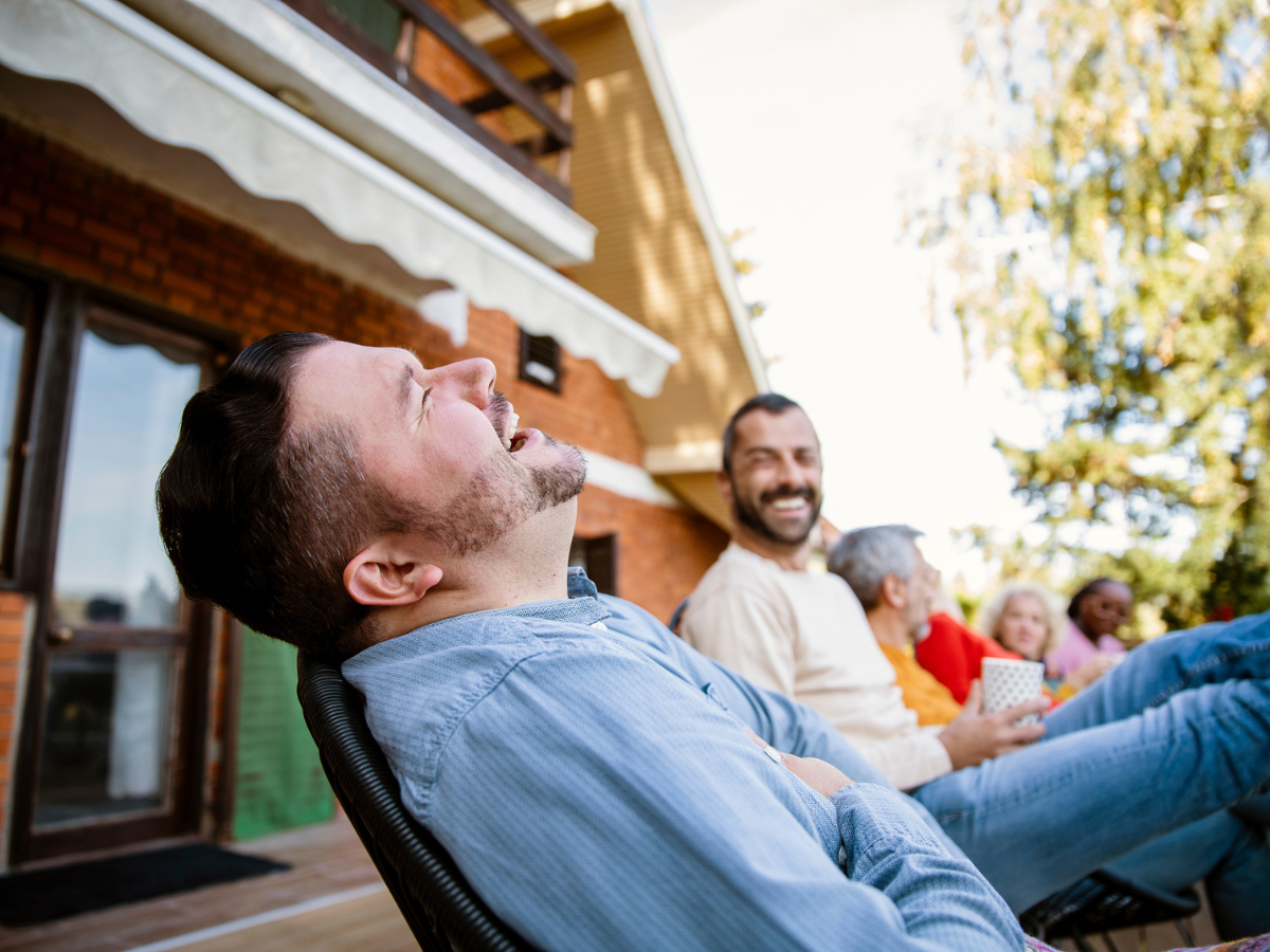 People enjoying outdoor seating near a house on a sunny day