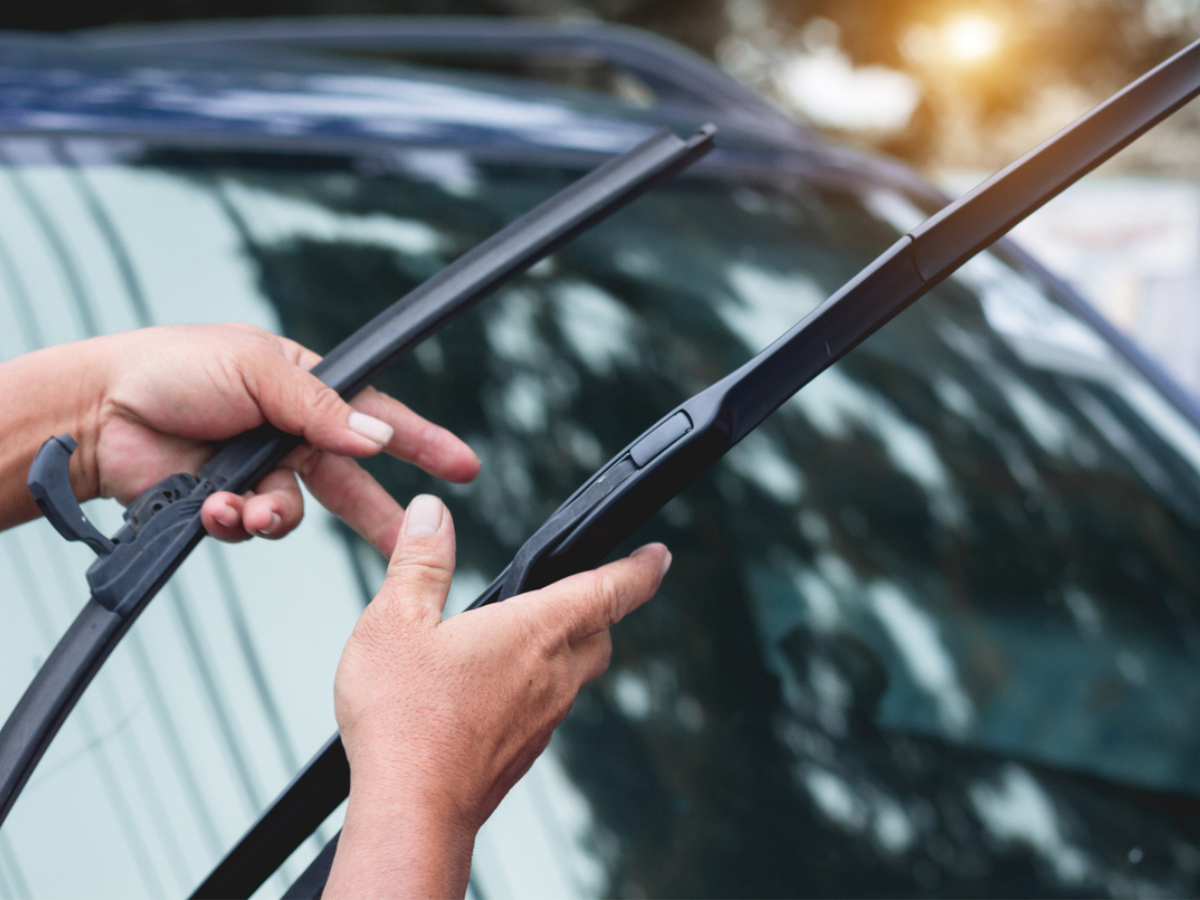Person fitting a new windshield wiper blade onto a car's wiper arm