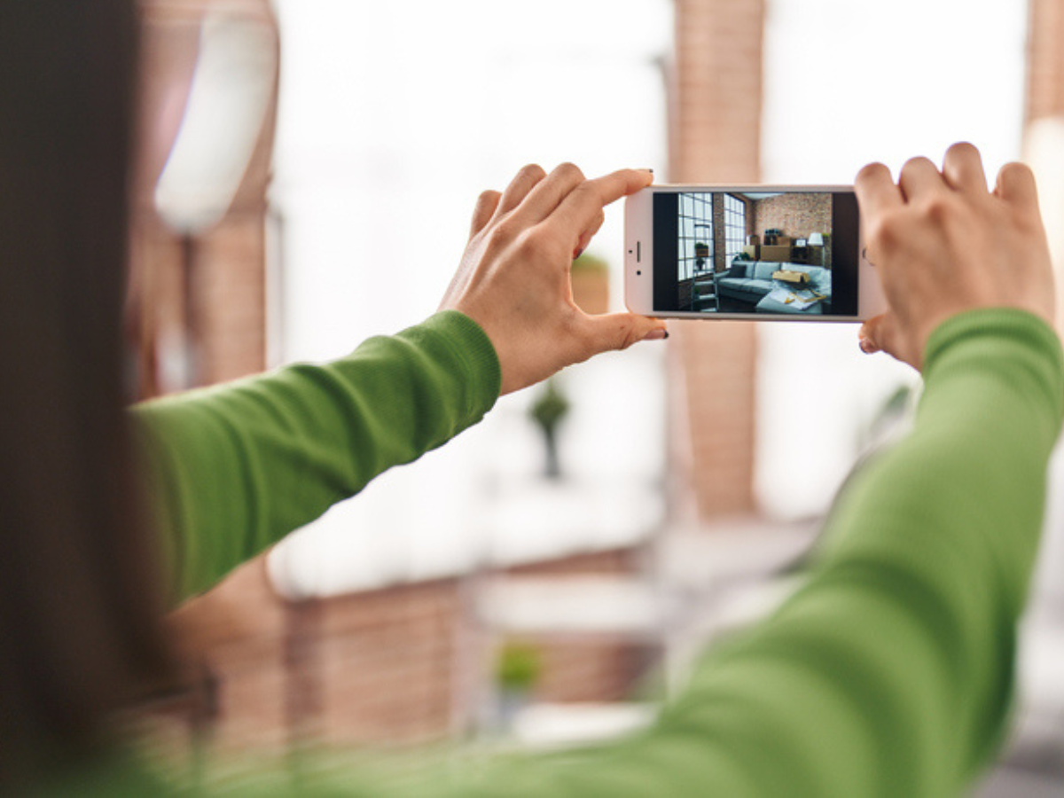 A person takes a photo of their living room with their phone.