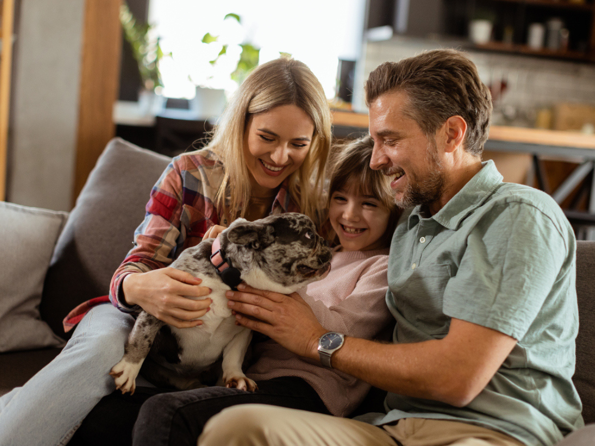 A family of three is petting their dog