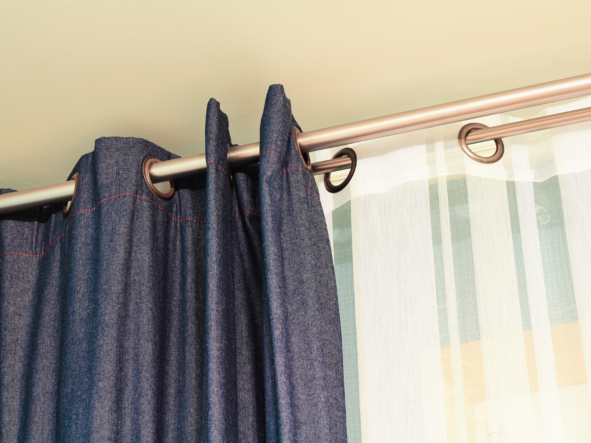 Tenant-installed blackout curtains and sheer drapes hanging from a modern window rod