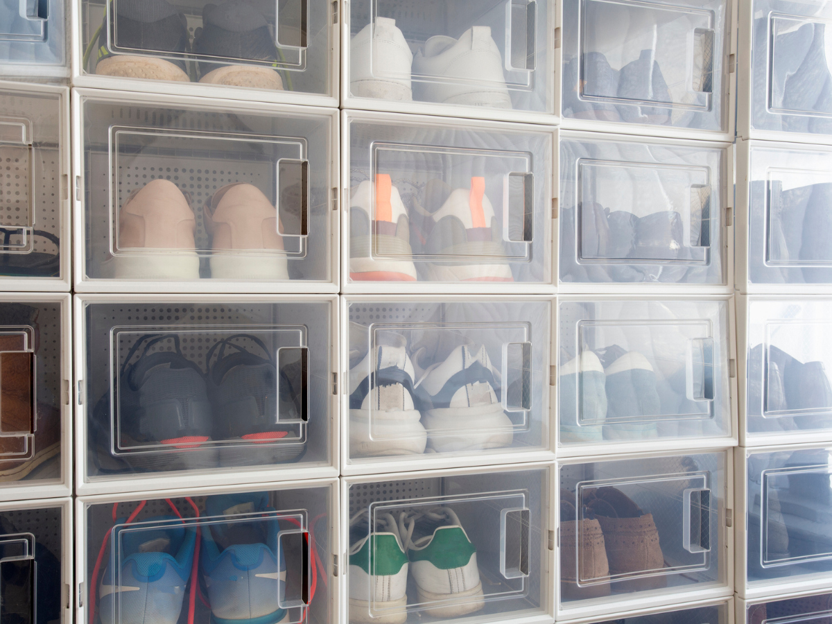Clear storage boxes neatly organized with shoes and footwear on shelving units.