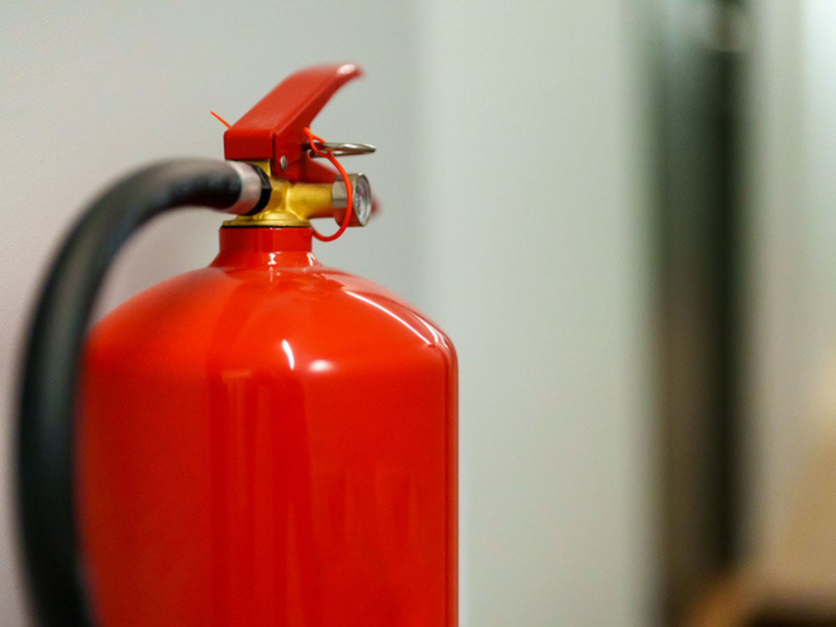 Red fire extinguisher mounted on a wall for Firework safety and emergency preparedness.