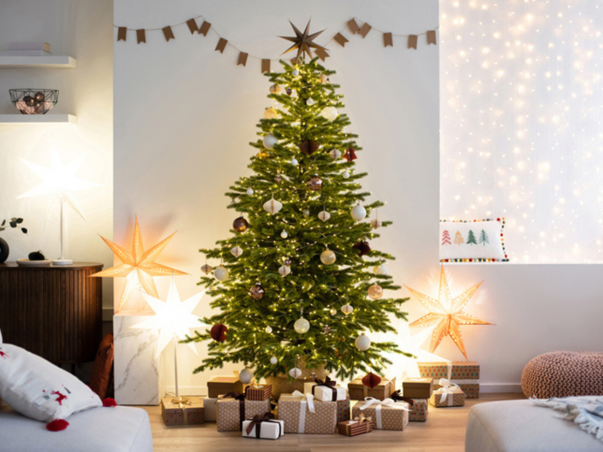 Decorated Christmas tree surrounded by wrapped gifts in a cozy living room.