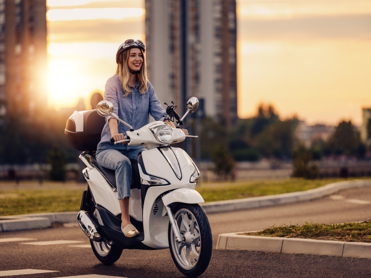 Rider on a white Motorcycle navigating a city street during sunset with urban buildings in the background