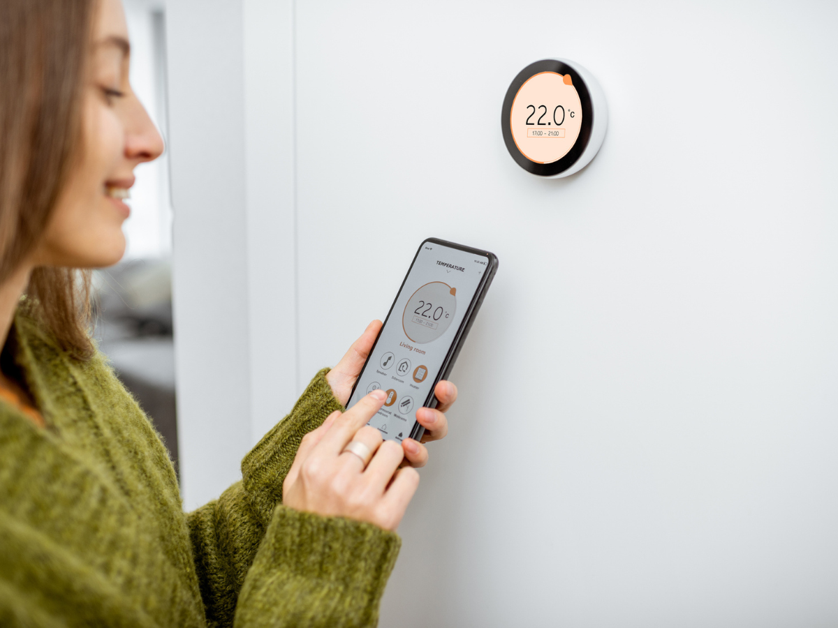 Homeowner adjusting a smart HVAC thermostat using a mobile app