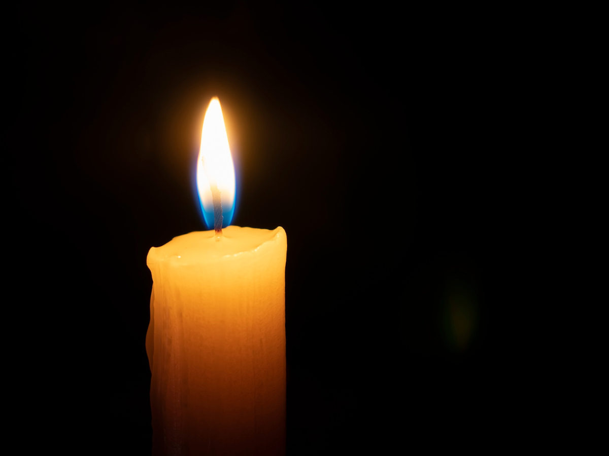 Lit candle burning against a dark background