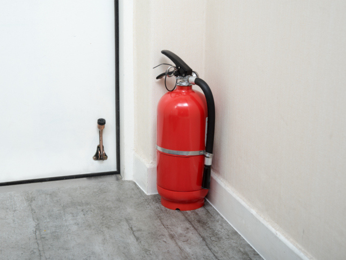 Fire extinguisher positioned near a door for Cabin and Cottage fire safety preparedness.