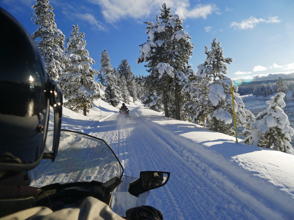 Point of view snowmobile ride on snowy trail with winter trees