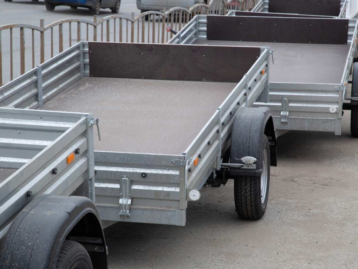 A row of empty utility trailers parked outdoors, highlighting the types of transport equipment covered by utility trailer insurance.