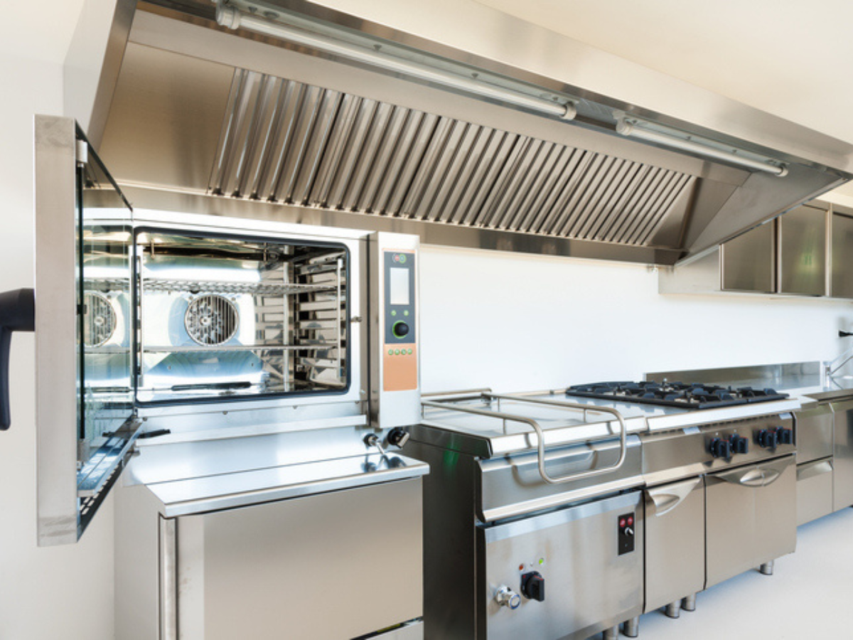 A clean, modern commercial kitchen with stainless steel appliances and ventilation system, emphasizing the value of restaurant insurance to protect essential equipment and operations.