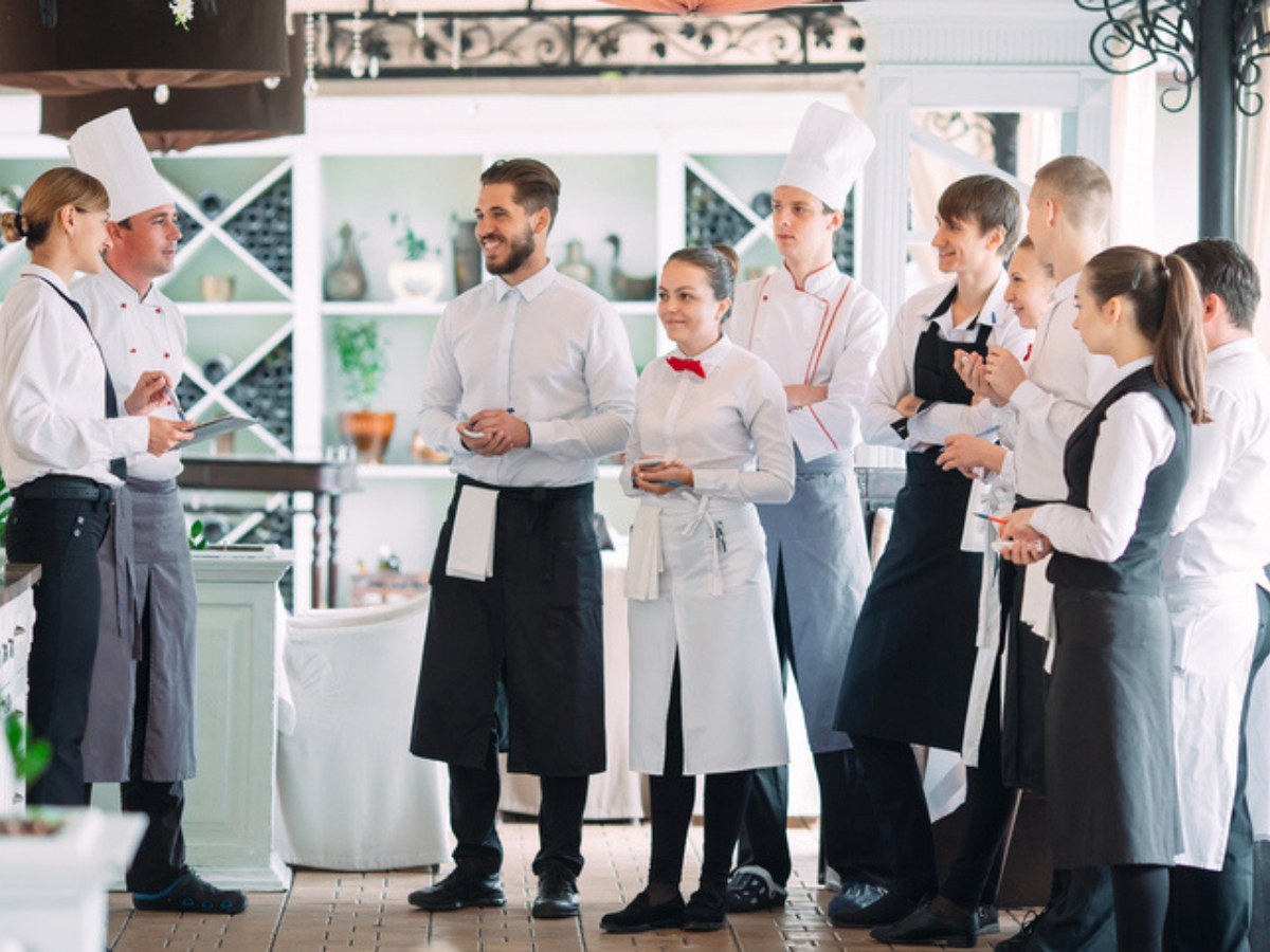 Group of restaurant employees standing together, emphasizing the importance of employee safety and workers compensation in the restaurant industry, covered by restaurant insurance.