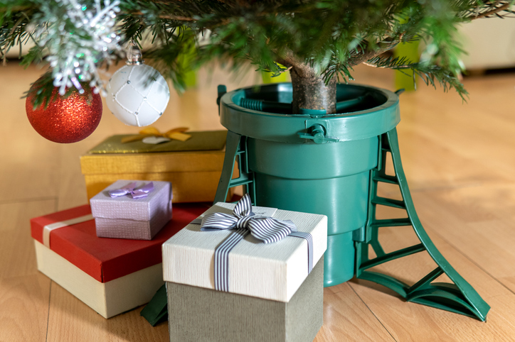 Natural christmas tree in stand with presents around it