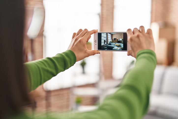 A person takes a photo of their living room with their phone.