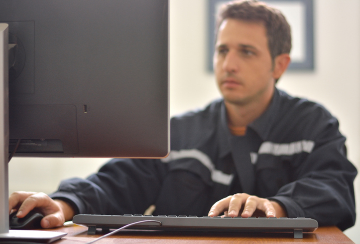 Tradesperson on computer in contractor's shop with cyber insurance