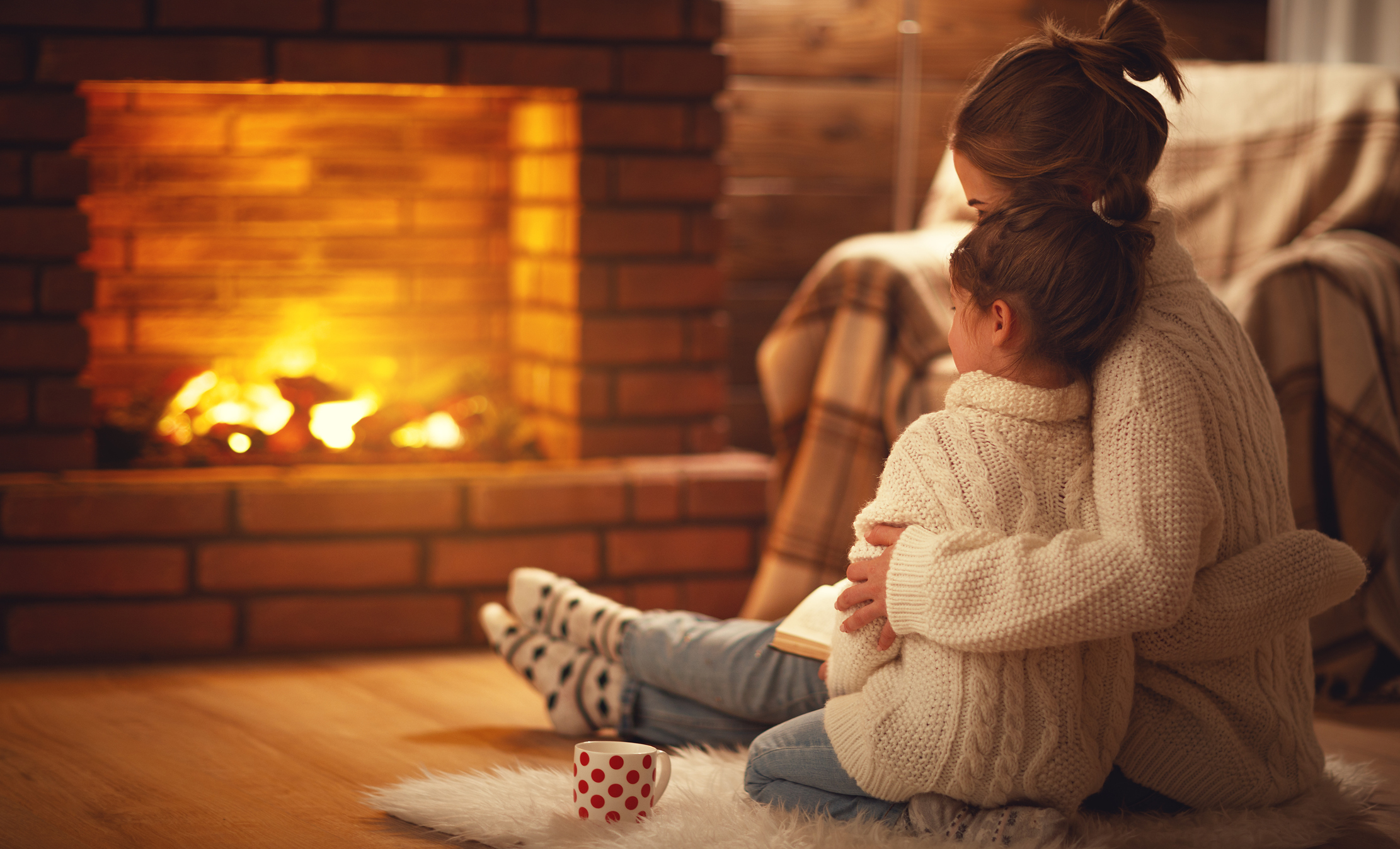 A mother and daughter sit by the fireplace of their home