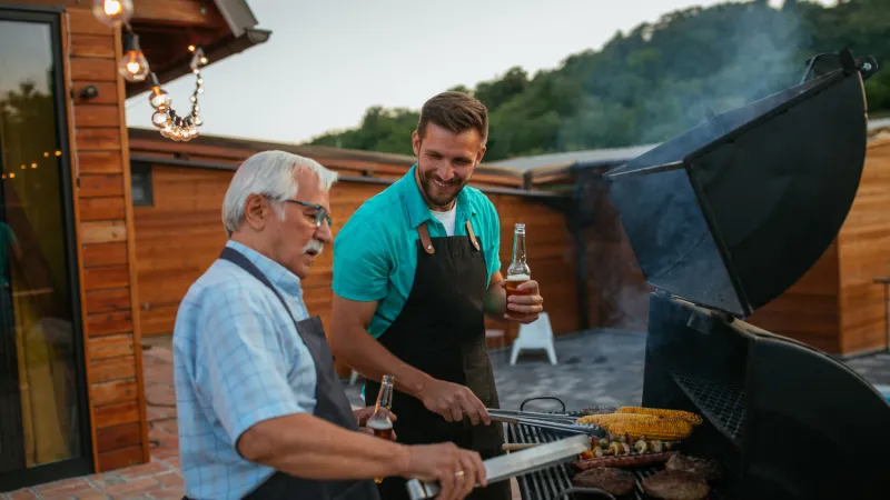 Two people using a BBQ