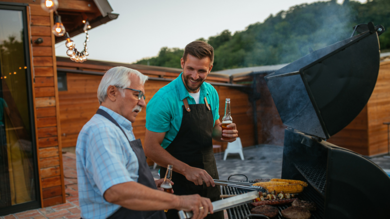 Two people using a BBQ