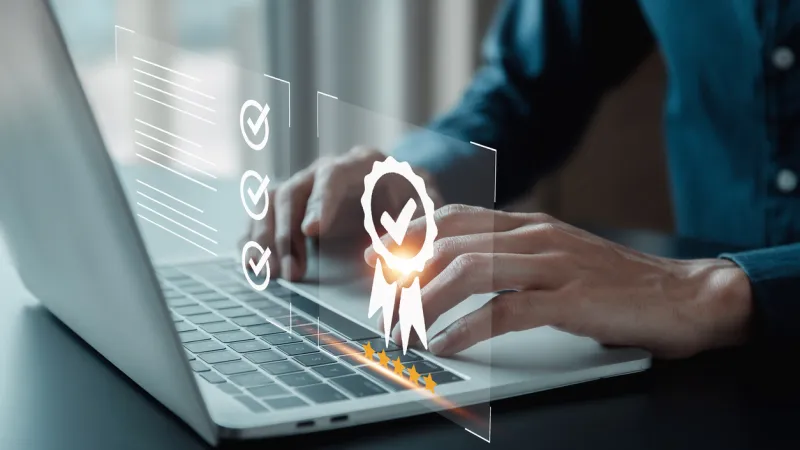 Hands typing on laptop with quality guarantee graphic.