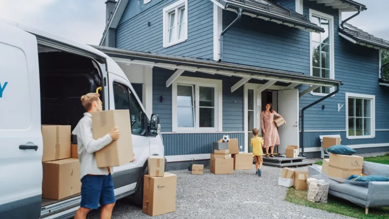 A family unloading moving boxes outside a new house while researching how much is home insurance in BC.