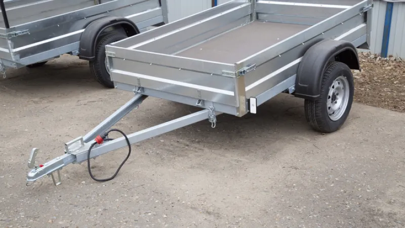 A newly manufactured open utility trailer parked outdoors, highlighting why you need proper utility trailer insurance