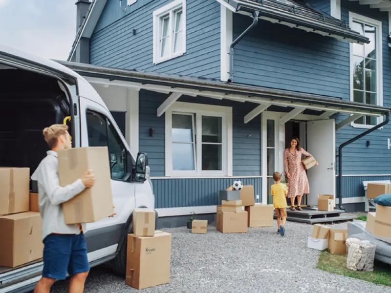 A family unloading moving boxes outside a new house while researching how much is home insurance in BC.