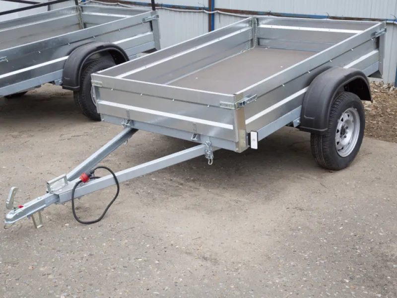 A newly manufactured open utility trailer parked outdoors, highlighting why you need proper utility trailer insurance